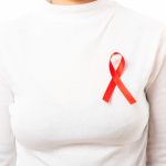 Kvinna med rött band på tröjan för att uppmärksamma hiv.