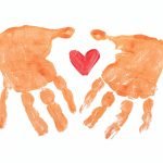 Avtryck av två händer i målarfärg med ett hjärta i mitten.