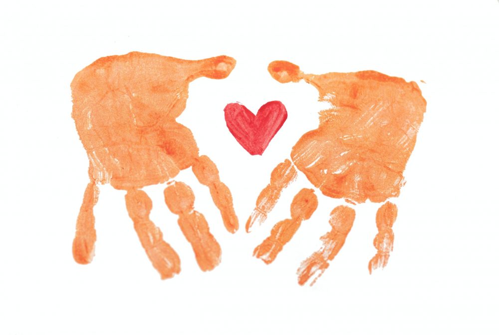 Avtryck av två händer i målarfärg med ett hjärta i mitten.