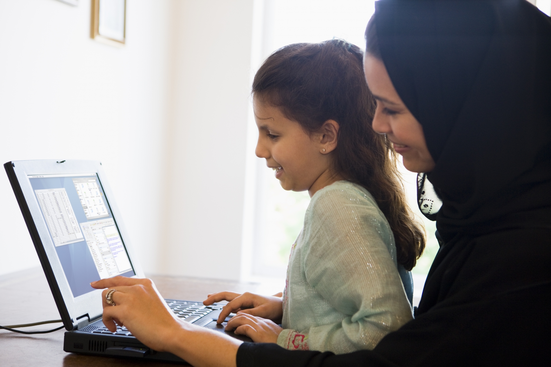 En kvinna och ett barn sitter vid en dator